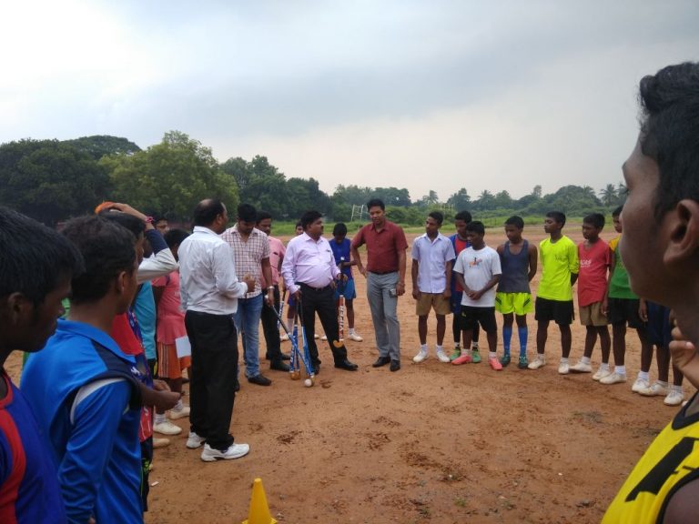 Lazrus Barla distributes hockey sticks among students in city